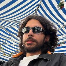 Silvio Rodrigues wearing sunglasses beneath a striped canopy